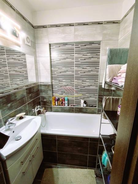 Bathroom in a 2-room apartment with a bathtub, sink, and a shelf with towels.