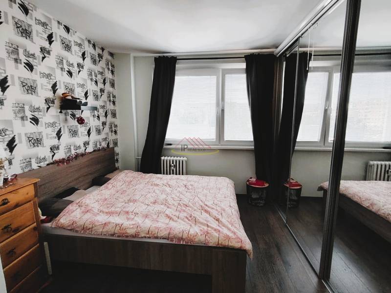 Bedroom in a 2-room apartment with a large window, sliding mirror doors, and a decorative wall.
