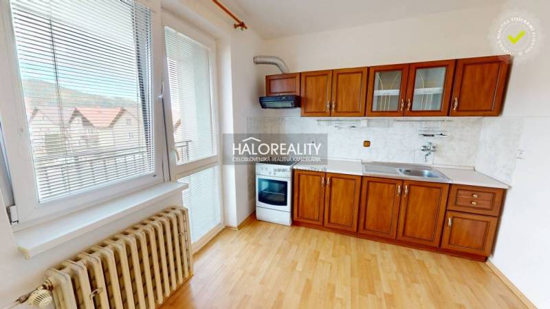 A kitchen with a kitchenette and a studio apartment with a view features wooden cabinets and a radiator.
