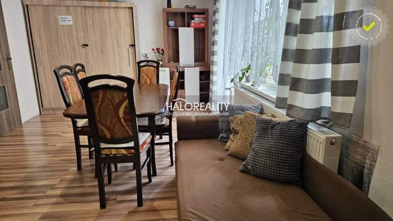 Dining room in a family house with a wooden table, chairs, and a sofa, light curtains.