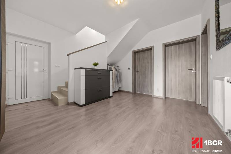 Hallway with stairs and three doors in a 4-room apartment with a chest of drawers and a coat rack.
