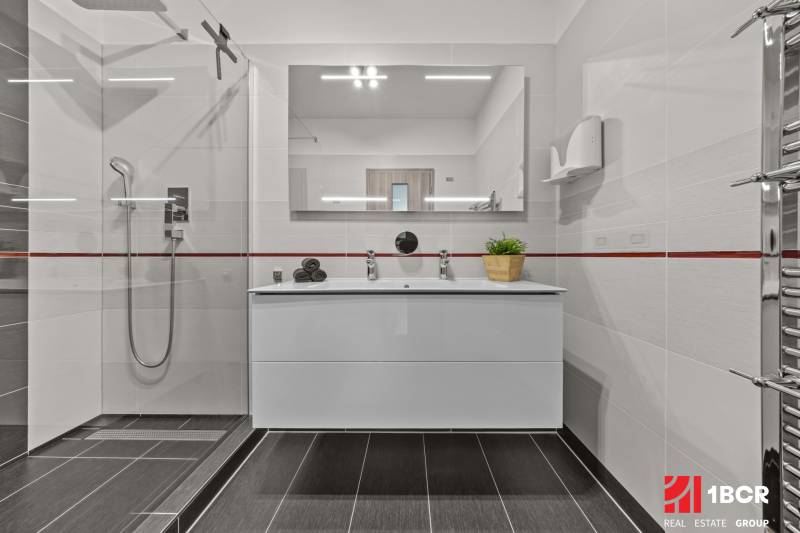 Bathroom with a sink, shower, and mirror in a 4-room apartment.