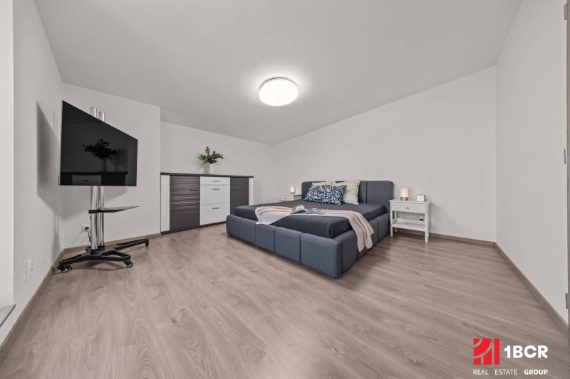 A bright bedroom with a large bed, a television, and a dresser in a 4-room apartment.