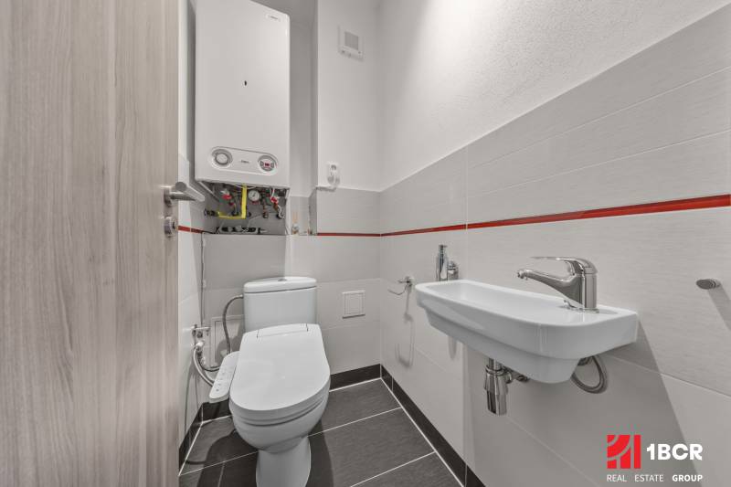 Bathroom in a 4-room apartment with a toilet, sink, and a boiler on the wall.