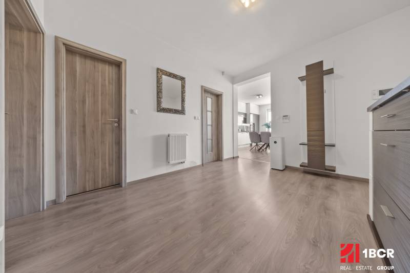 Hallway of a 4-room apartment with wooden doors, a mirror, and a view into the kitchen.