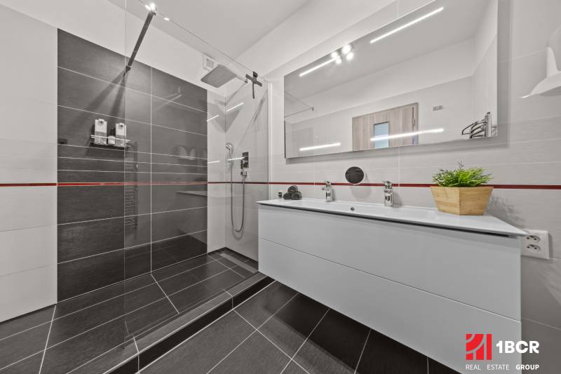 A bathroom in a 4-room apartment with a shower and a double sink.