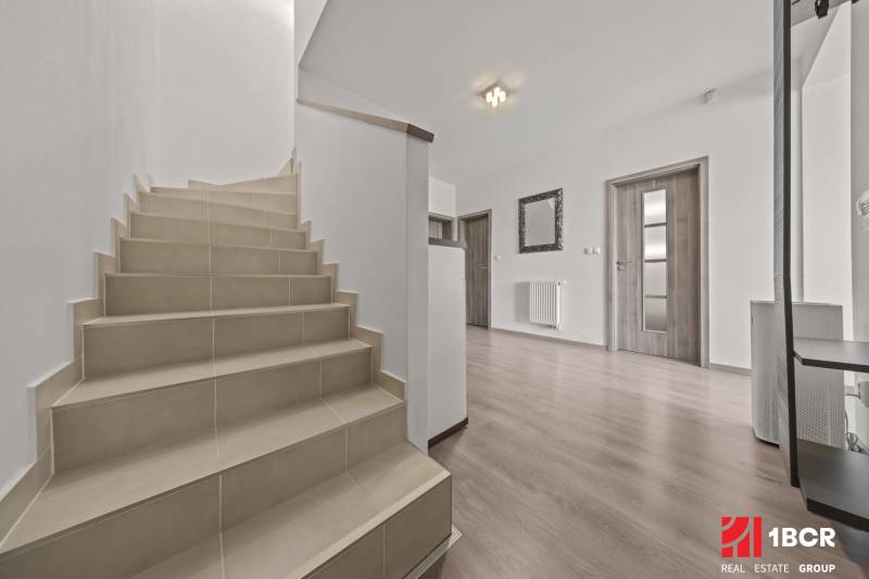 A staircase in a 4-room apartment with wooden flooring and white walls.