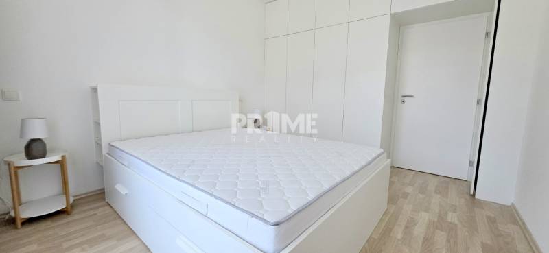 Bedroom in a 2-room apartment with white furniture and a built-in wardrobe.