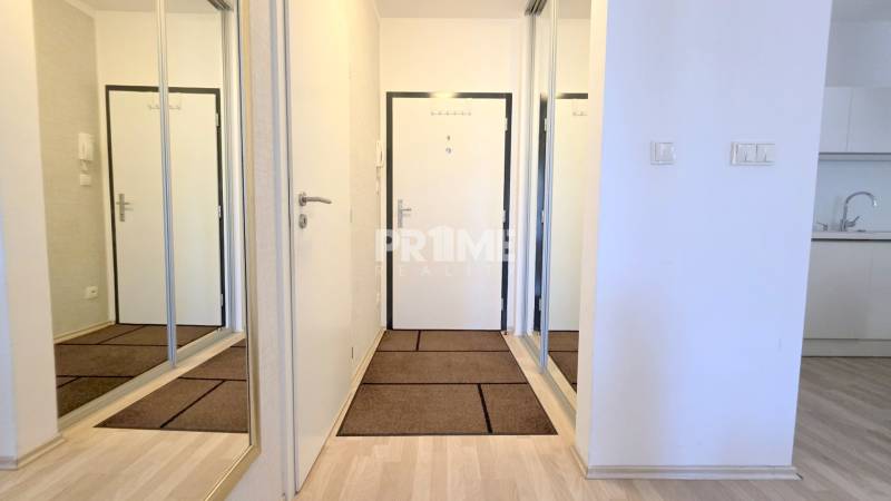 Entrance hallway in a 2-room apartment with a large mirrored wardrobe and white walls.
