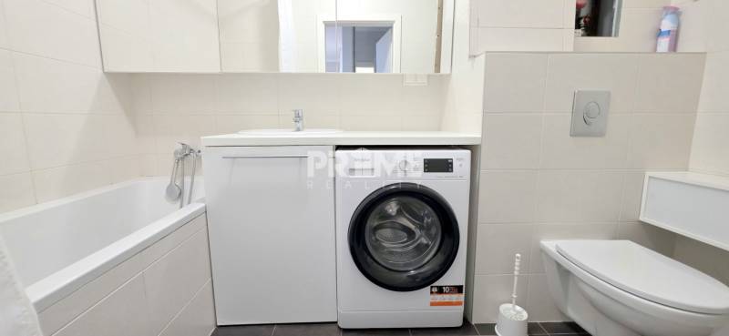 Bathroom in a 2-room apartment with a bathtub, washing machine, and toilet.