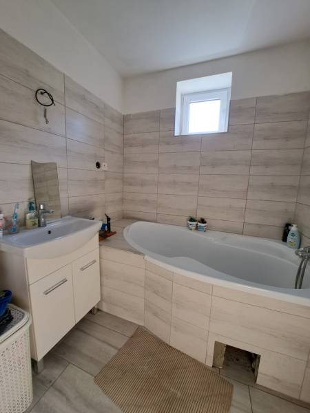 A bathroom in a family house with a bathtub and a sink in light shades.