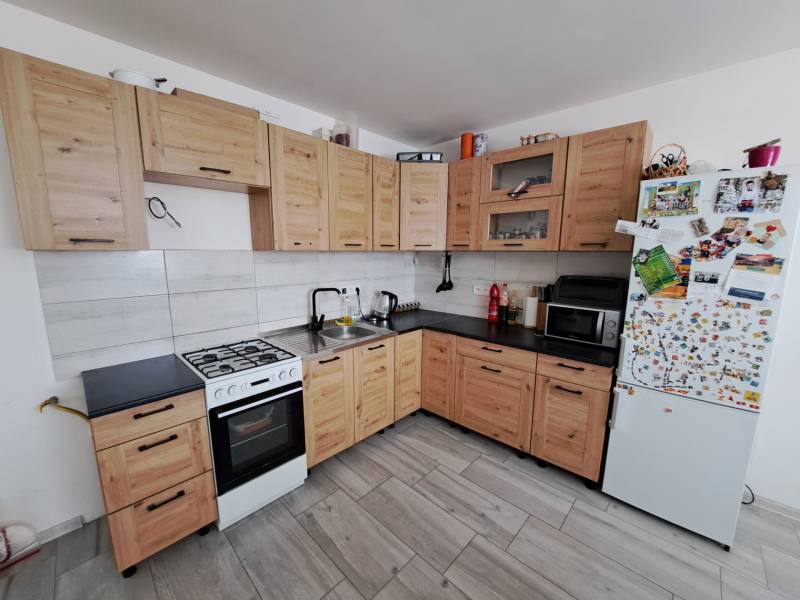 A kitchen in a family house with light wooden cabinets, a white refrigerator, and an electric stove.