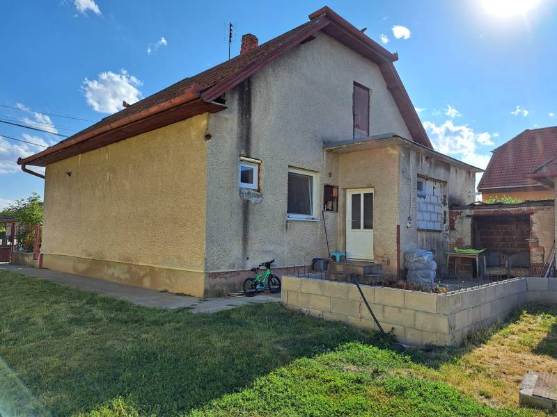 A family house in Kmeťovo with a terrace, garden, and stored items by the house.