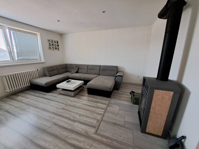 Living room with a corner sofa, fireplace stove, and a table in a family house.
