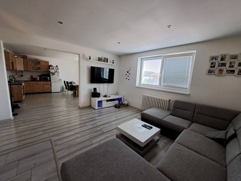 Living room with a kitchen in a family house with a sofa, television, and wooden cabinets.