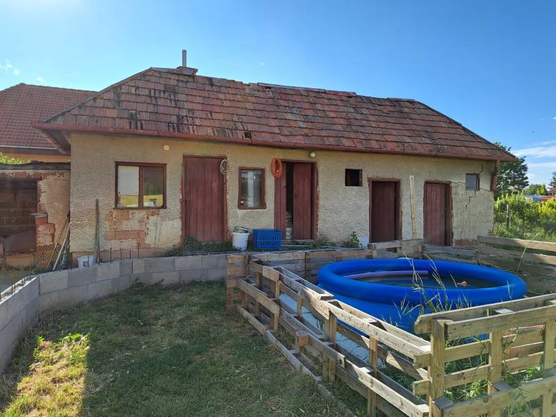 Family house in Kmeťovo with an extension, inflatable pool, and simple wooden fence.