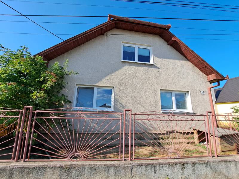 A family house in Kmeťovo with a white facade and a metal fence.