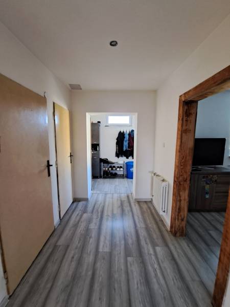 A hallway in a family house with laminate flooring, wooden door frames, and a shoe storage.