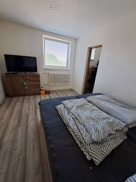 A room in a family house with a television, a sofa, and a window bringing in natural light.