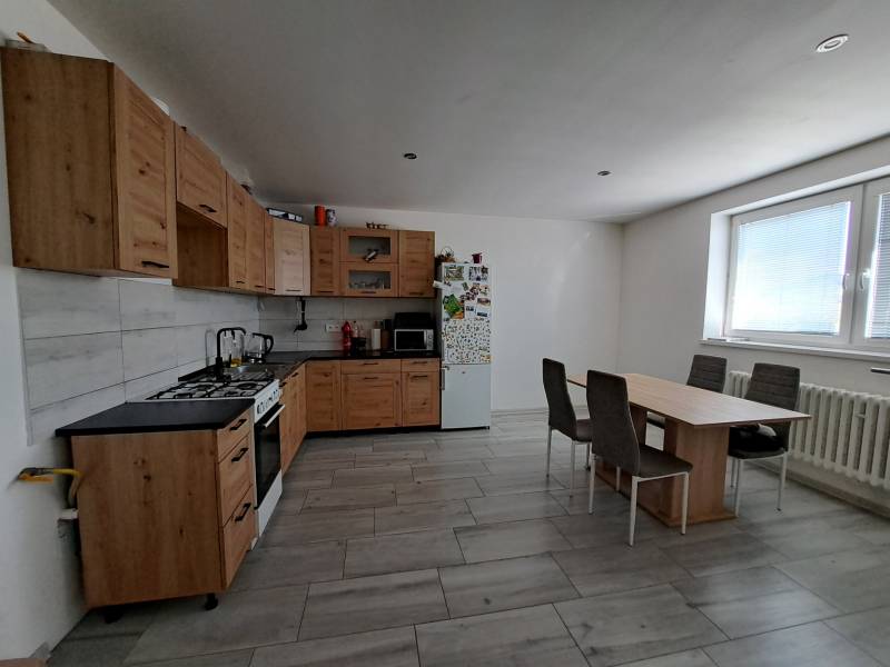 A kitchen in a family house with wooden cabinets, a dining table, and appliances.