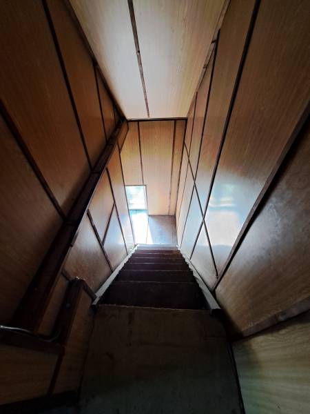 A staircase with wooden walls leading to a narrow window in a family house.