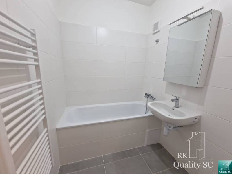 A bathroom in a 4-room apartment with a bathtub, a sink, and white tiles.