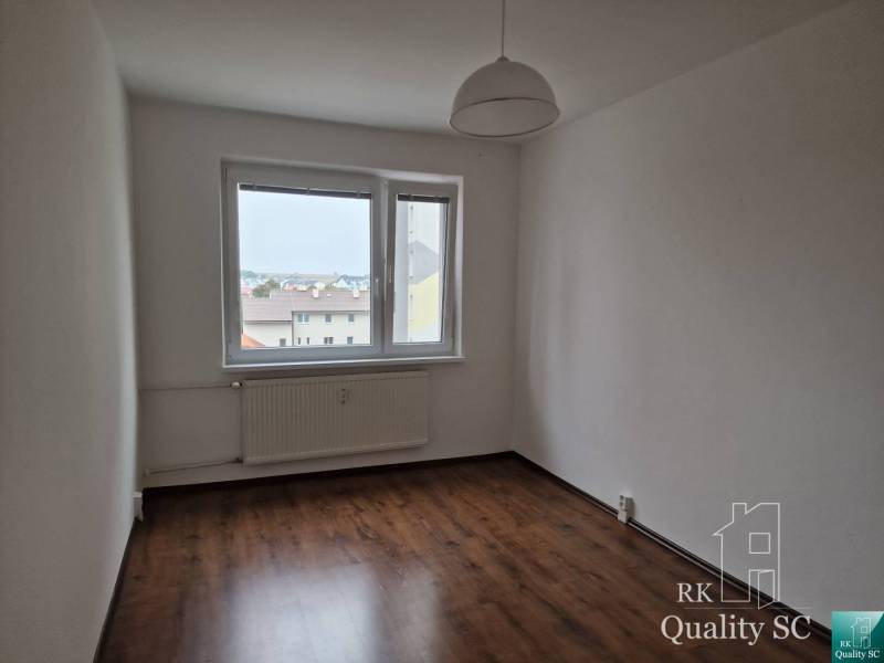 A room in a 4-room apartment with laminate flooring and a simple pendant lamp.