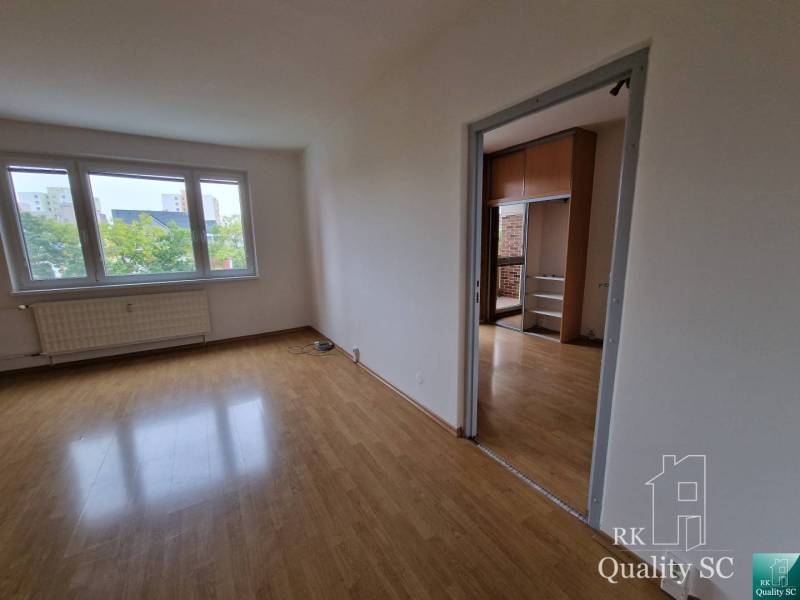 A spacious room with wooden flooring and large windows in a 4-room apartment.
