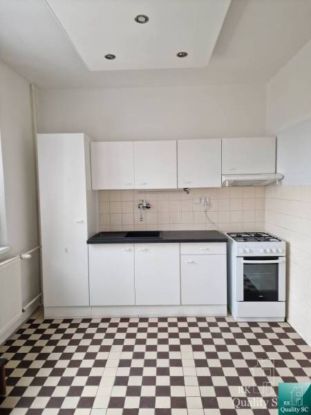 A kitchen in a 4-room apartment with white cabinets and tiled flooring.