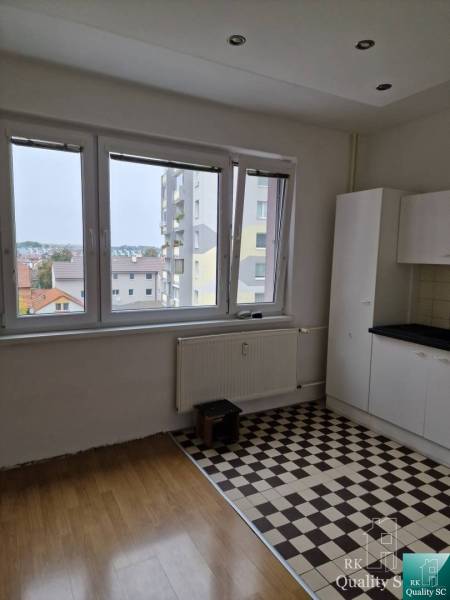 A kitchen in a 4-room apartment with wooden and tiled floors, light through a large window.