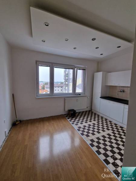 Living space in a 4-room apartment with patterned flooring and a kitchen unit.