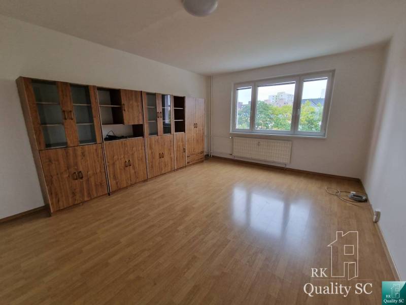 A spacious room with wooden floors and a large glass cabinet in a 4-room apartment.