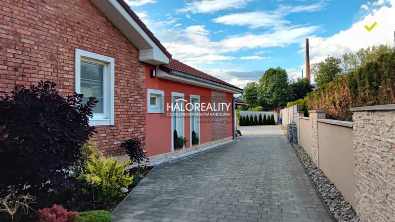 A family house in Kalinovo with a brick facade, a paved walkway, and a landscaped garden.