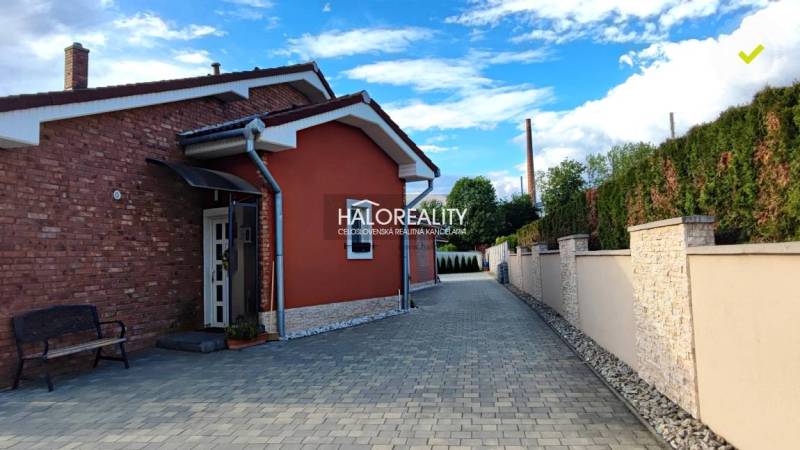 A family house in Kalinovo with interlocking pavement and a brick facade, enclosed by a wall.