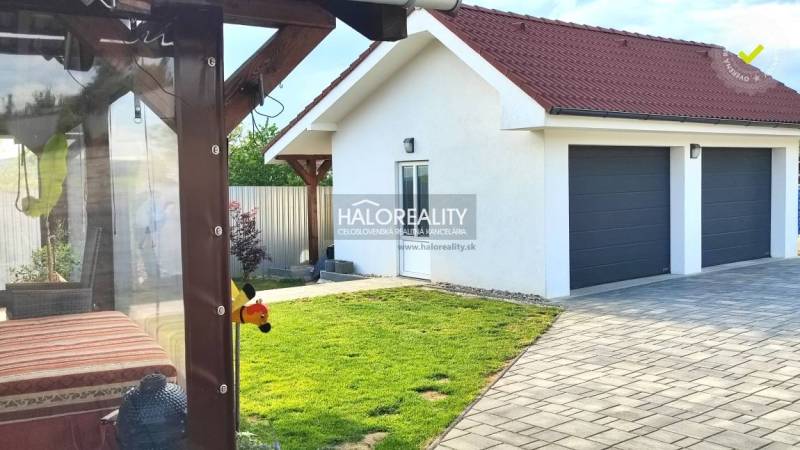 The exterior of a family house in Kalinovo with a lawn, terrace, and double garage.