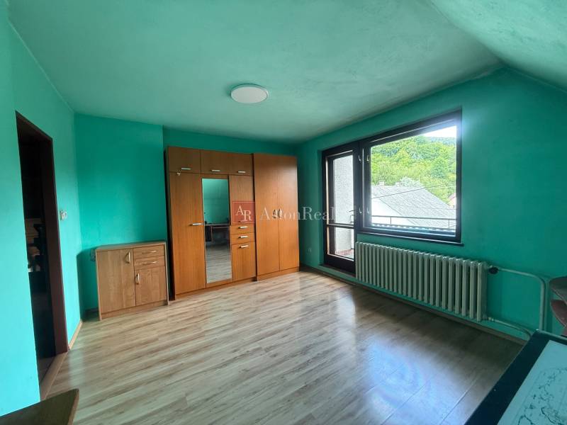 A room in a family house with a wooden floor, a wardrobe, and a balcony window.