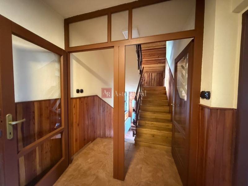Wooden staircase and doors in a family house with paneled walls and tiles.