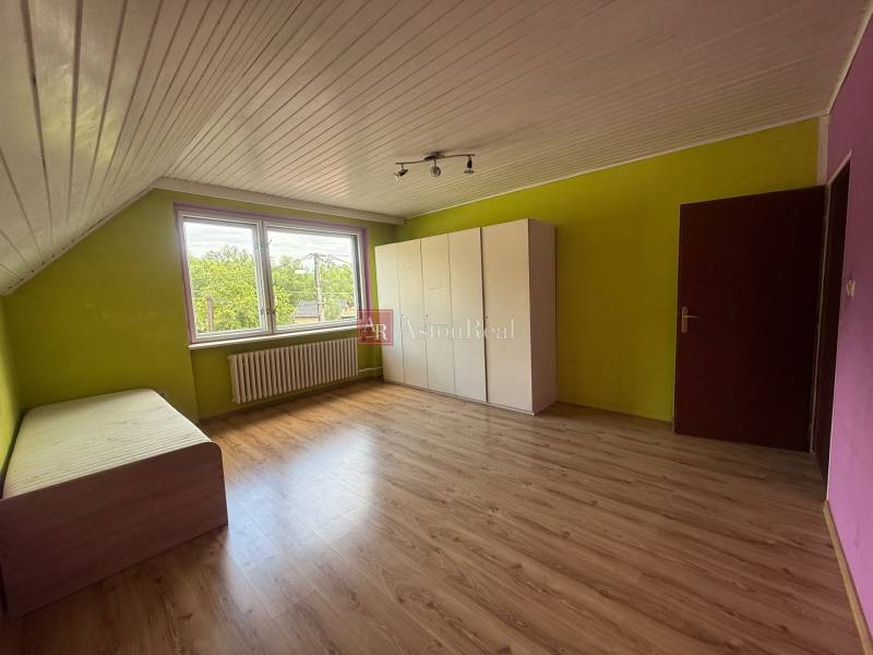 A room in a family house with laminate flooring, colorful walls, a bed, and a wardrobe.
