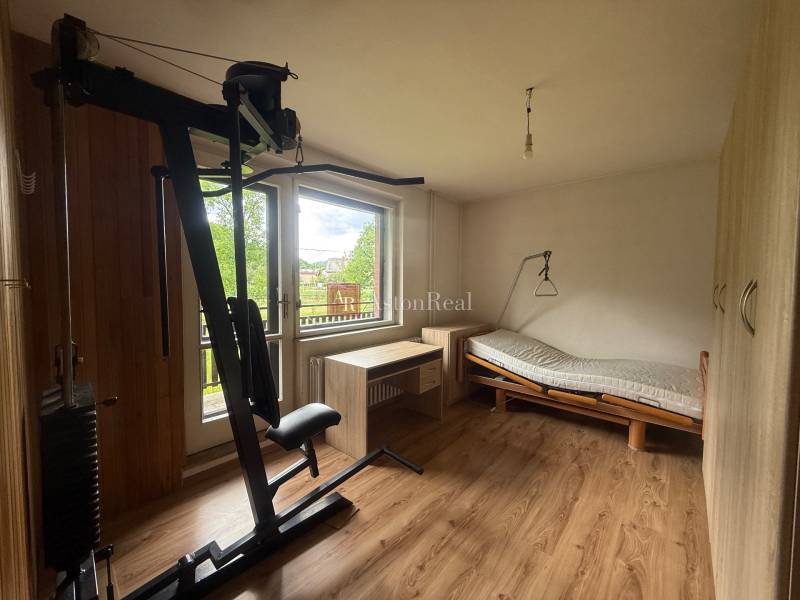 Exercise machine, bed, and desk in a room of a family house.