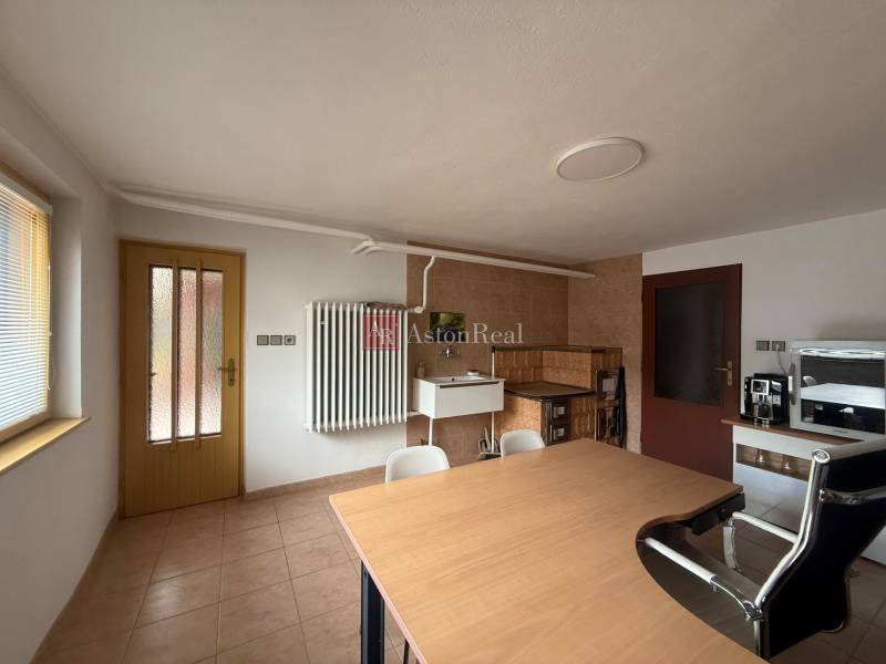 Interior of a family house with a wooden table, chairs, a tiled stove, and doors.