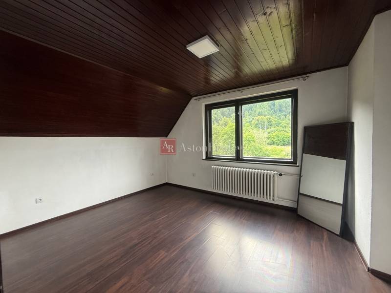 A spacious room in a family house with a wooden ceiling and a view of nature.