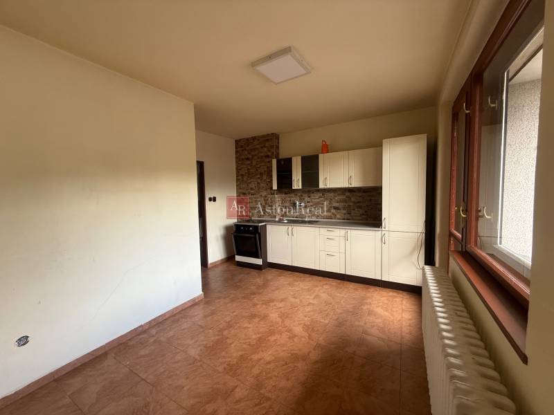 A kitchen in a family house with white cabinets, a stove, and a window with a radiator.
