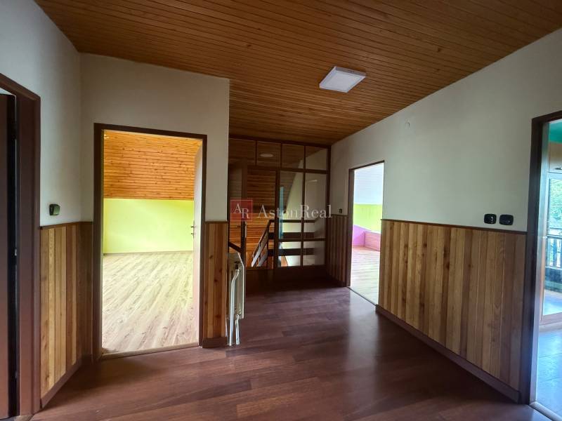 A hallway in a family house with wooden paneling and a view of colorful rooms.