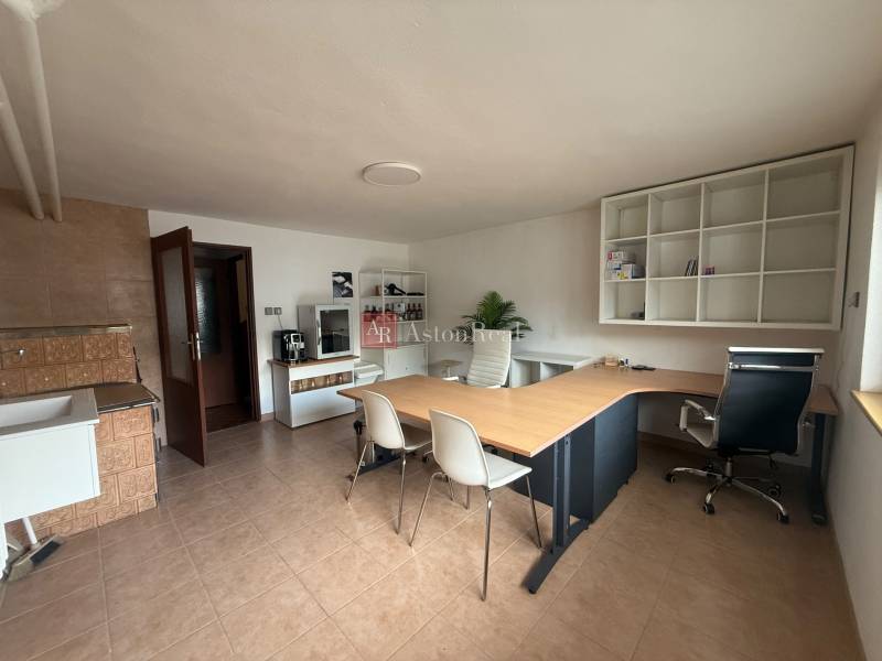 Office in a family house with a large desk, shelves, and a kitchenette.