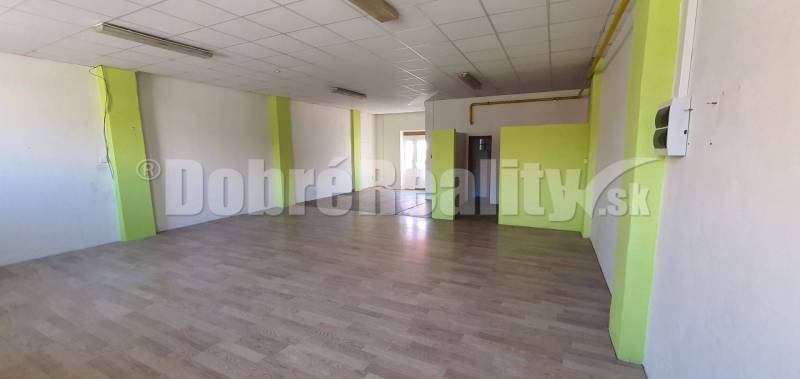 Spacious commercial spaces with laminate flooring and white walls with green stripes.