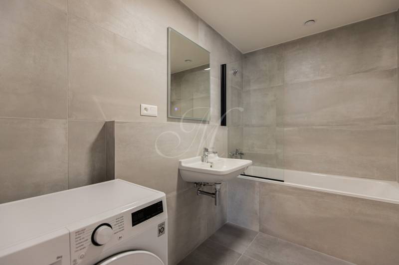 Bathroom with a bathtub and a washing machine in a 3-room apartment, light tiles and a sink.