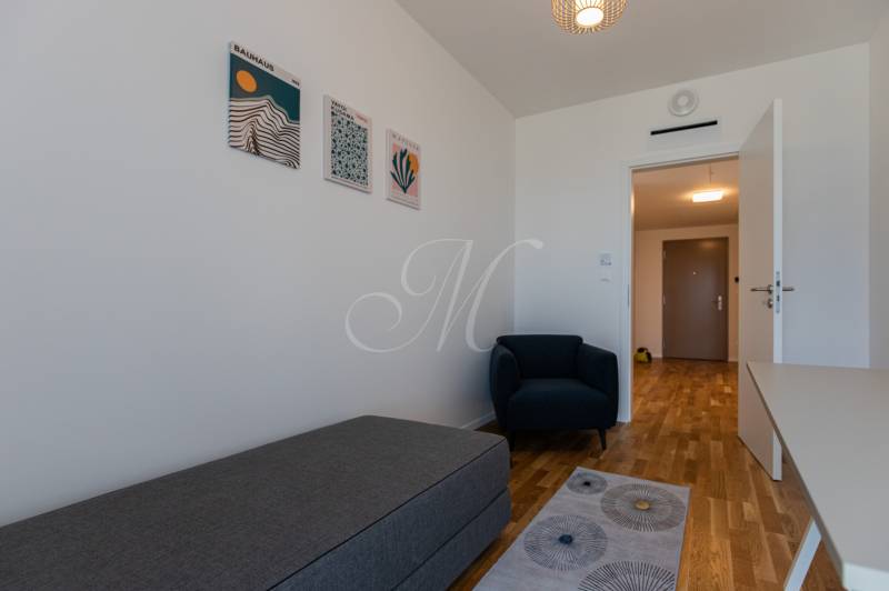 A room in a 3-room apartment with an armchair, laminate flooring, and wall paintings.