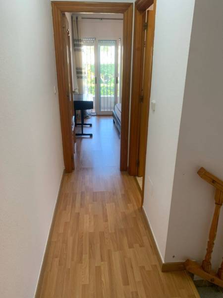 The hallway of the family house leads to a room with a bed and a desk.