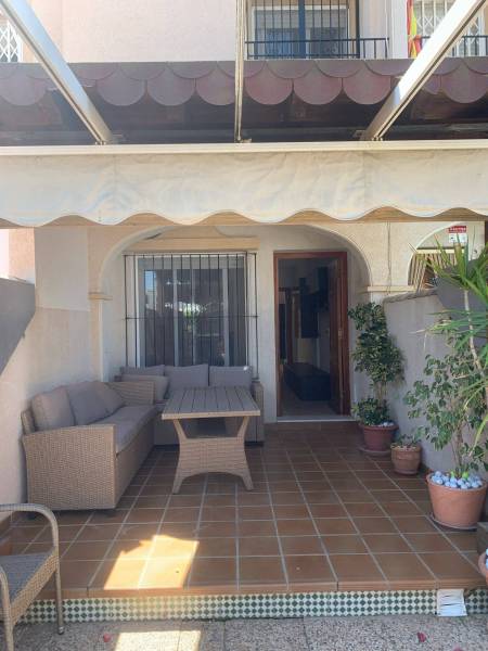A family house in Santiago de la Ribera with a terrace, wooden furniture, and flower pots.