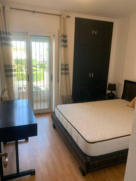 Bedroom in a family house with a bed, a desk, and access to a balcony.